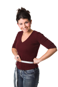 Pretty brunette looking very happy with a measuring tape around her waist